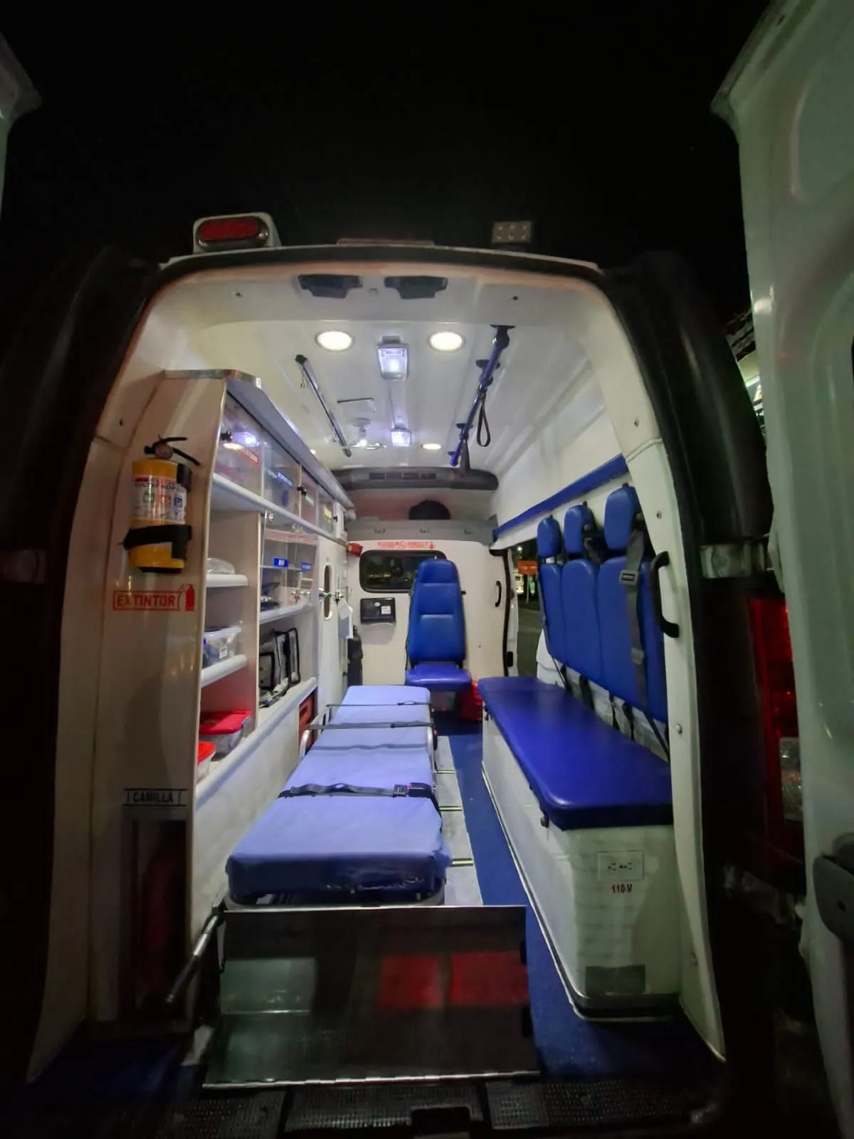 Ambulancia de ARUM con las puertas traseras abiertas lista para un servicio en la noche